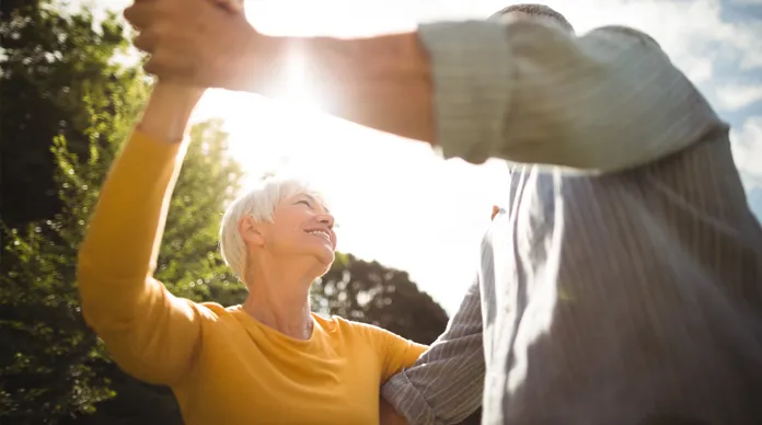 Symbolbild überwundene Angst - älteres Paar tanzt in der Sonne